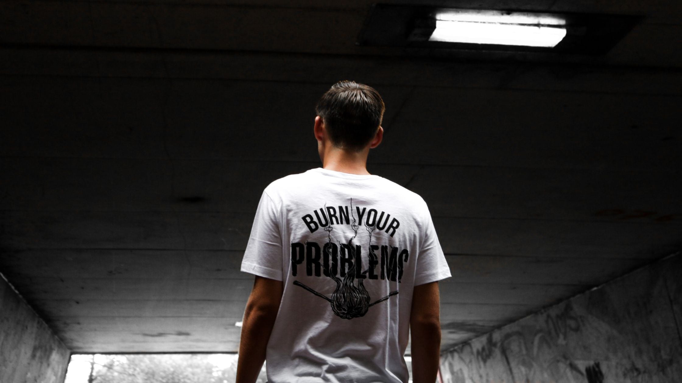 a man in a white graphic shirt, standing casually