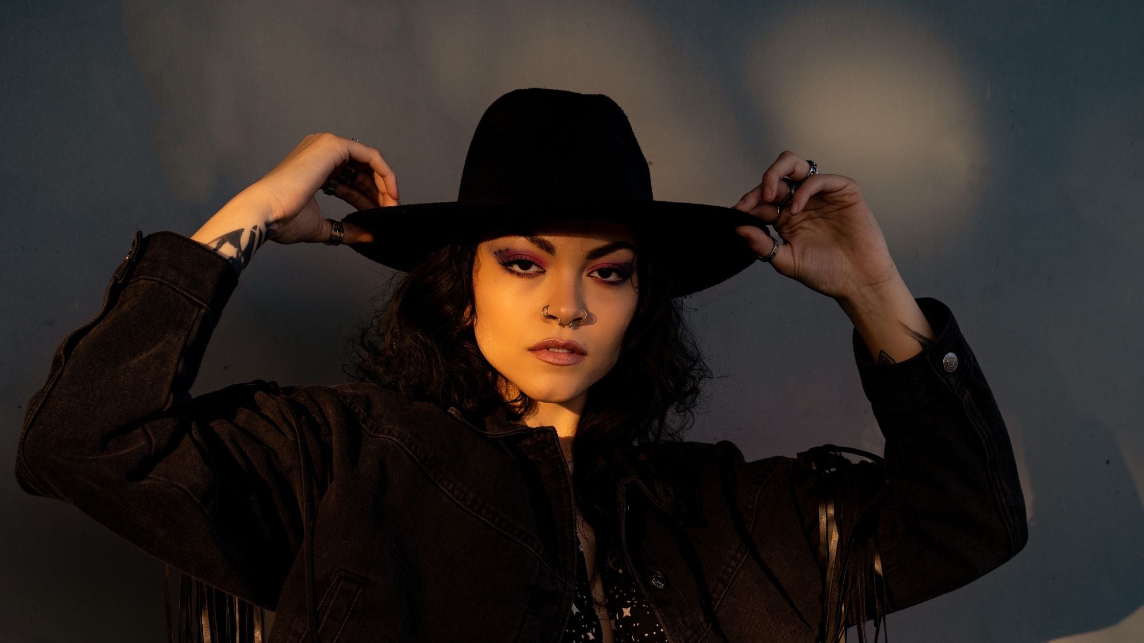 a woman wearing a stylish black cowboy hat and jacket