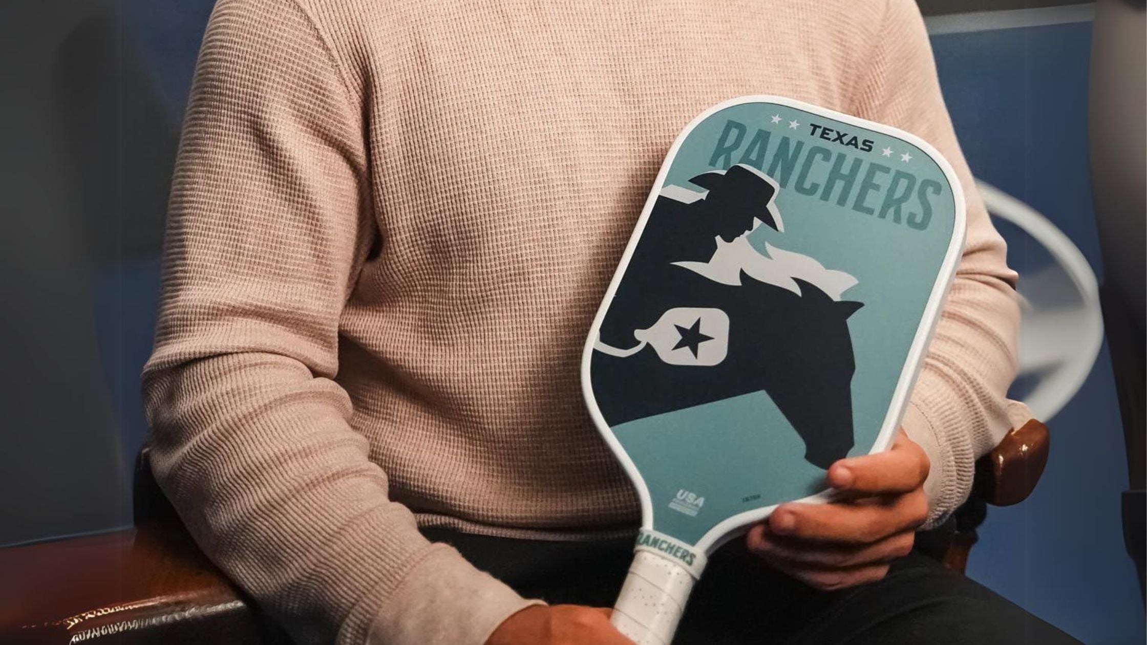 a man holding a paddle with a cowboy and horse design by Texas Ranchers