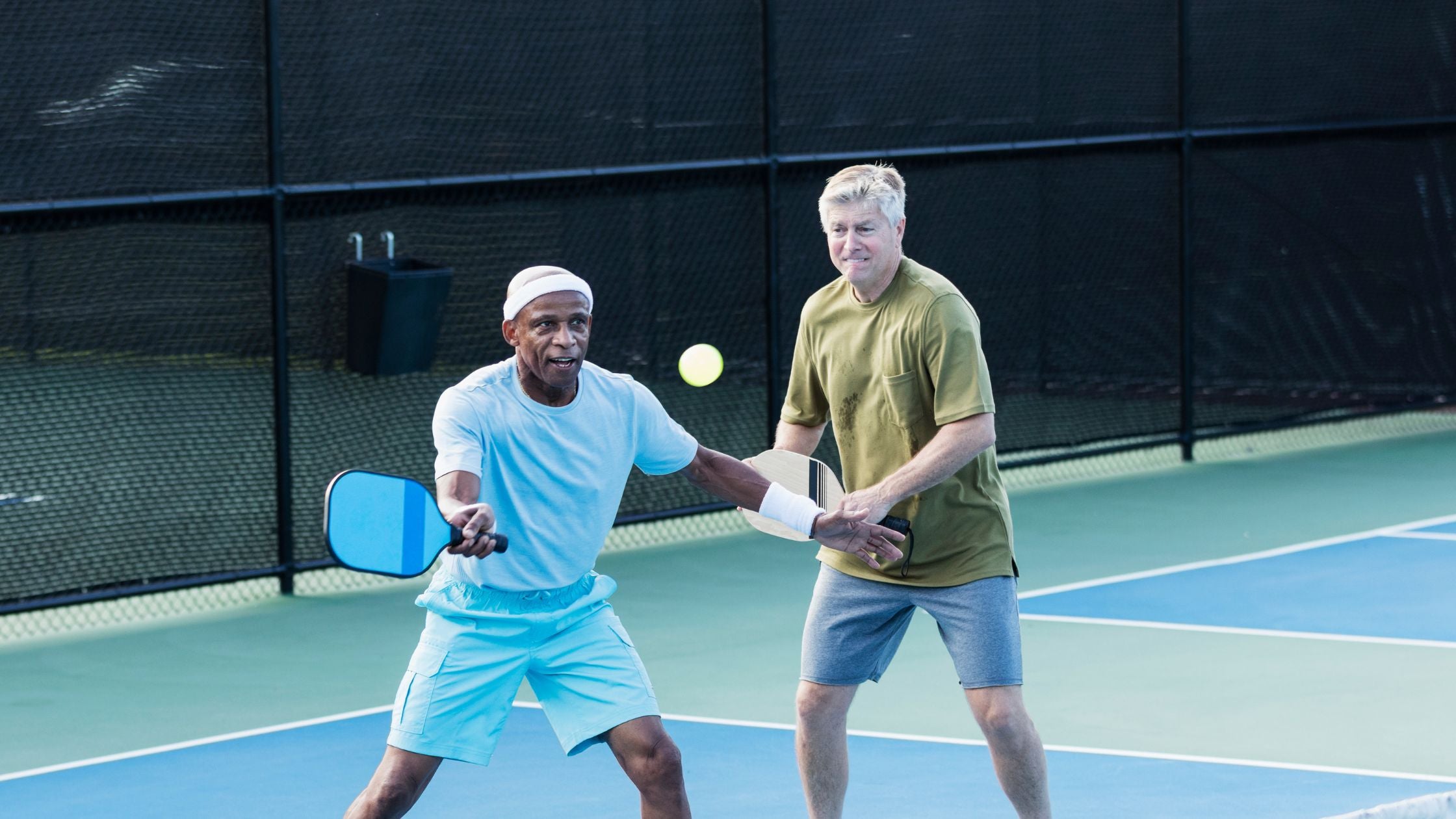 two old men playing pickleball on a court