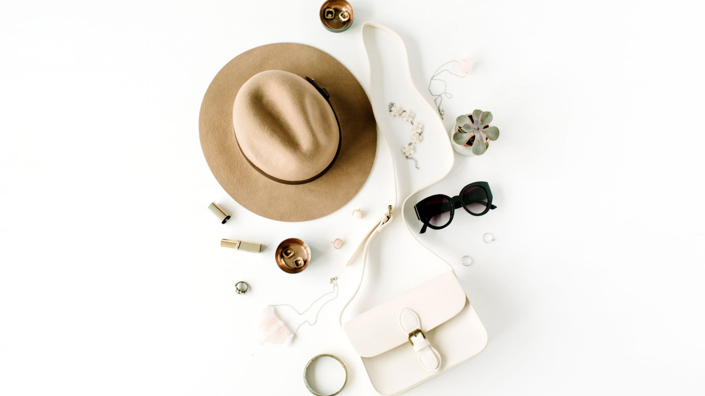 various accessories like a hat, earrings, sunglasses, and a purse displayed on a white surface