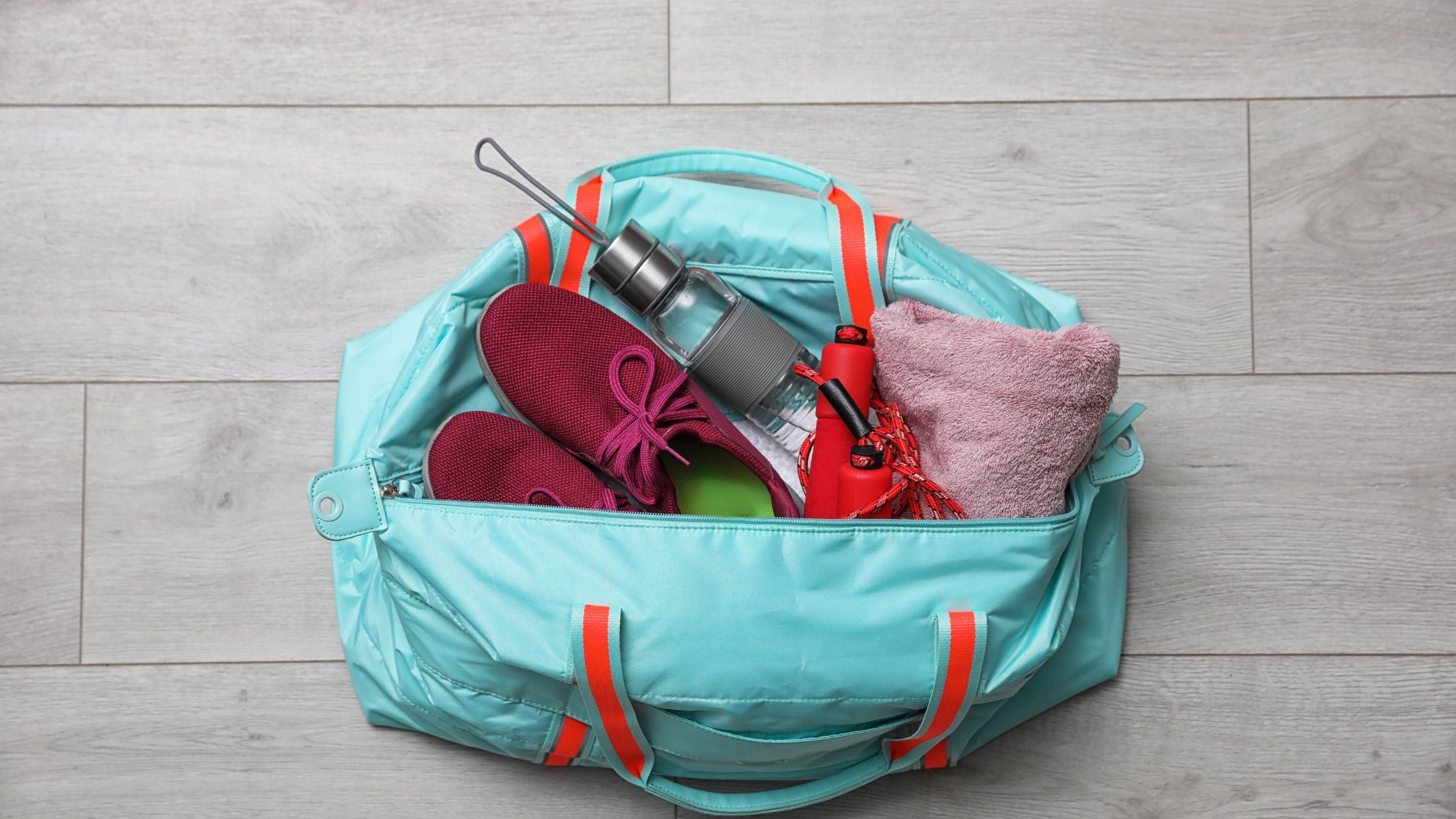 a variety of items in an open blue bag, including shoes, a water bottle, and a towel