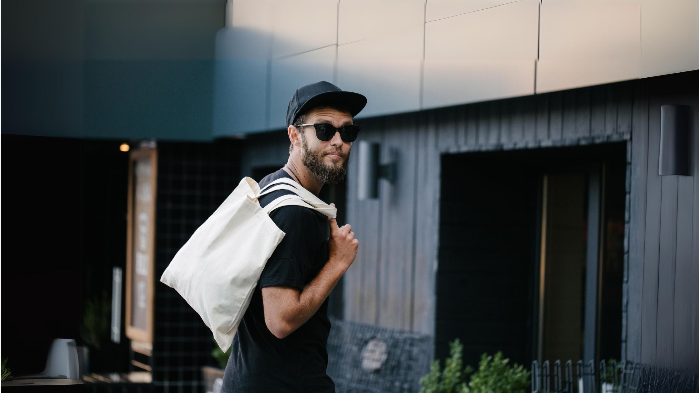 a man wearing sunglasses and holding a white tote bag