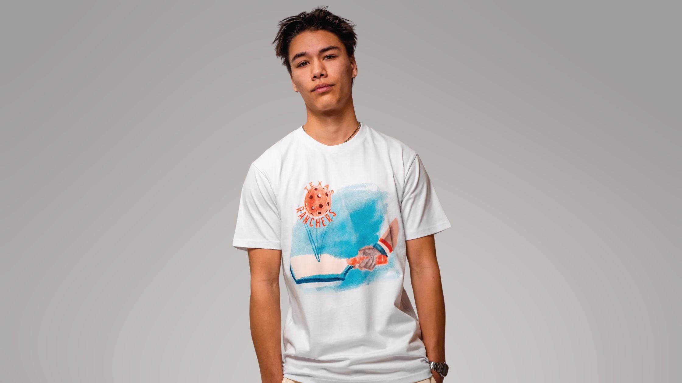 a young man wearing a paddle graphic tee by Ranchers