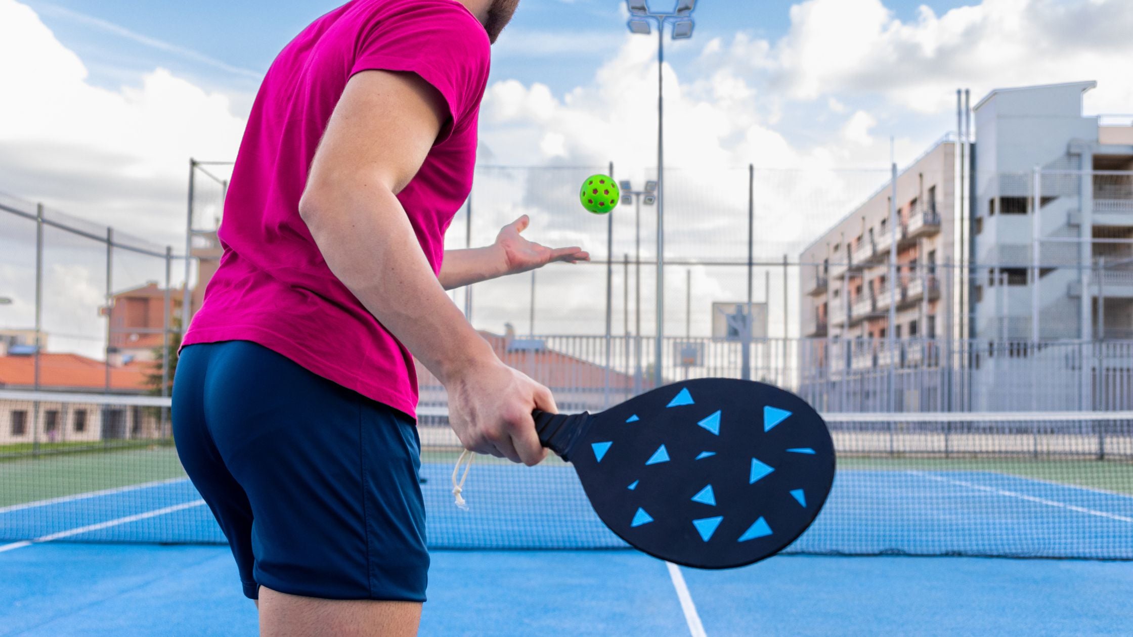 a man holding a pickleball paddle and ball