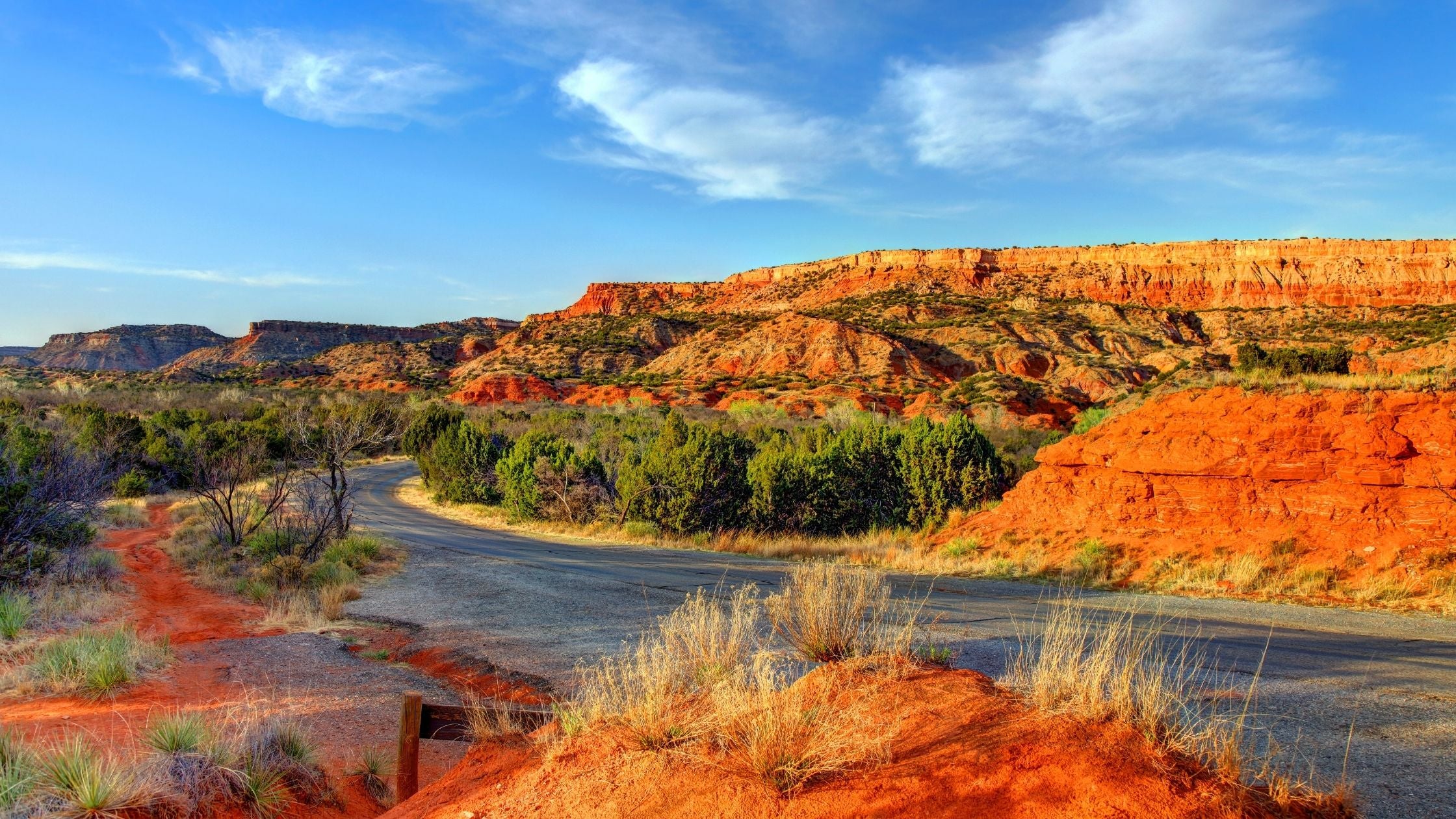 a scenic desert highway with red rock formations under a clear blue sky